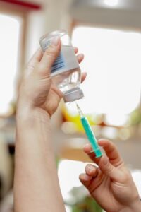 A person holds a syringe and a bottle, preparing for a cartilage and steroid injection procedure